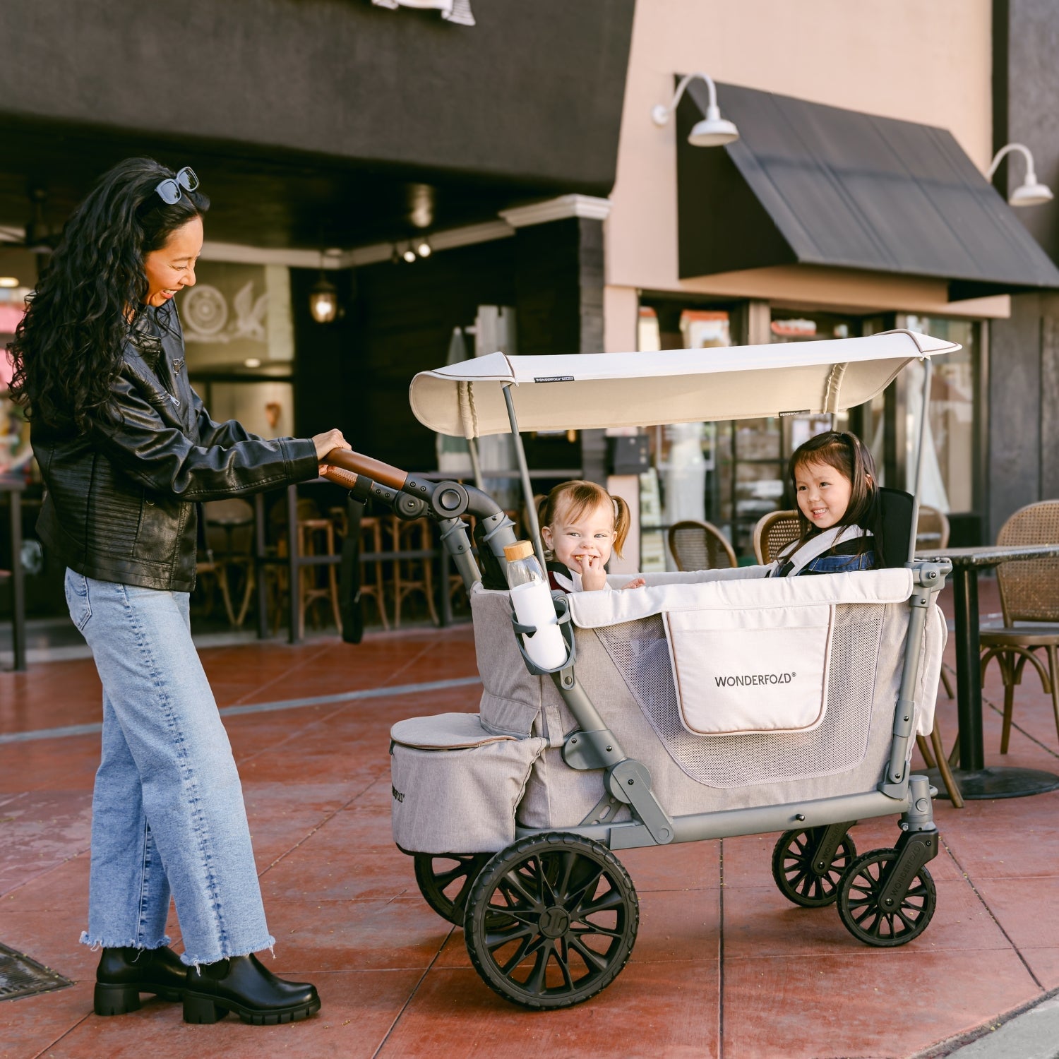 Woman pushing a stroller with two children in an outdoor setting